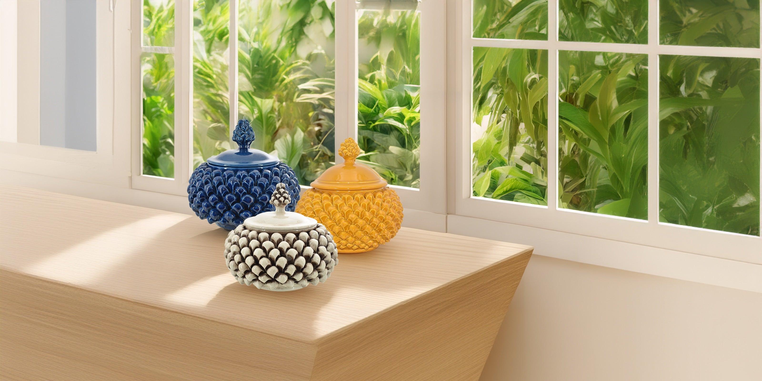 Biscottiere a pigna in ceramiche di Caltagirone fatti a mano, in blu, giallo e bianco, su tavolo vicino finestra