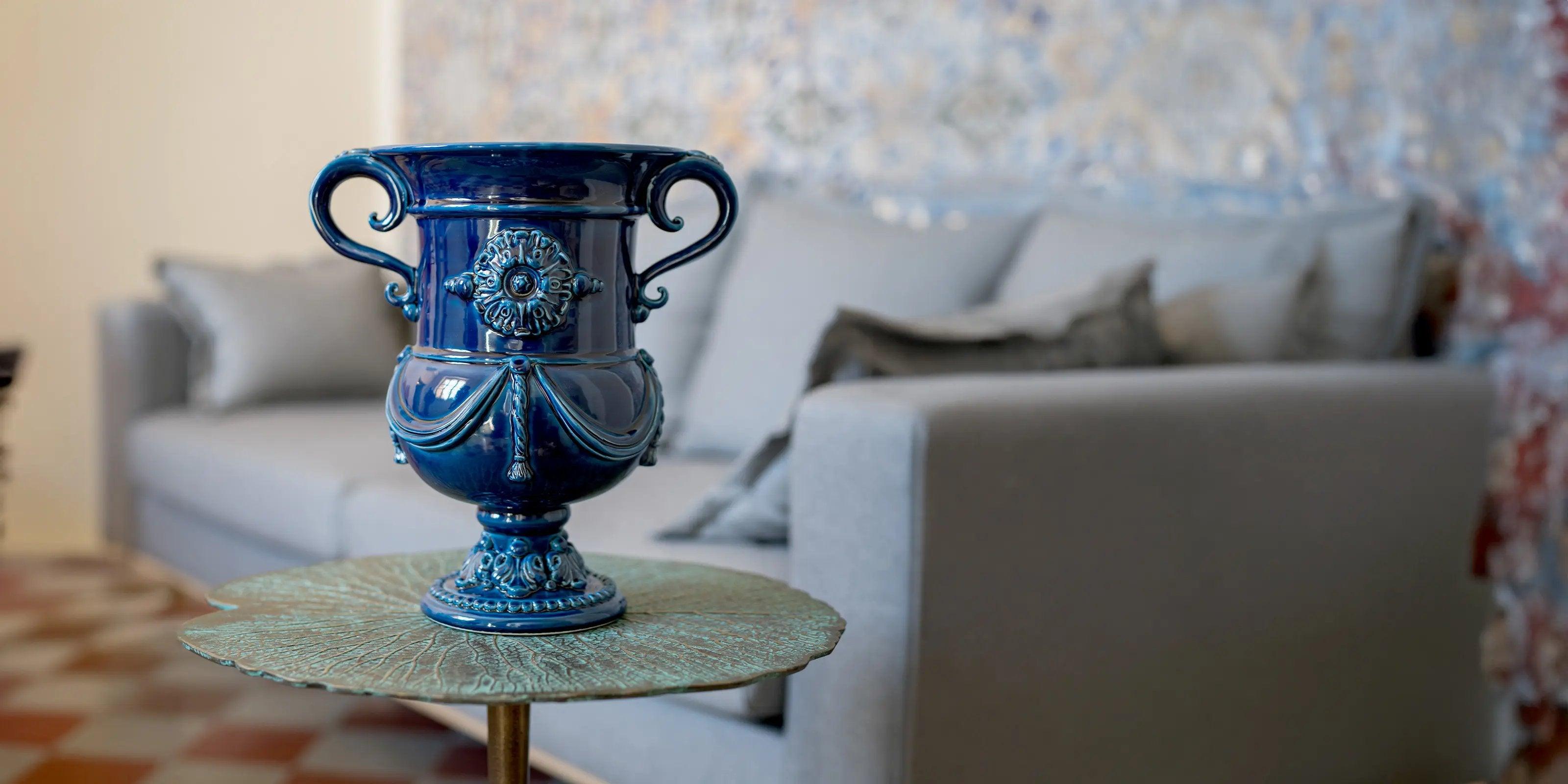 Vaso blu decorativo ceramiche di Caltagirone fatti a mano su tavolino con divano grigio sfondo