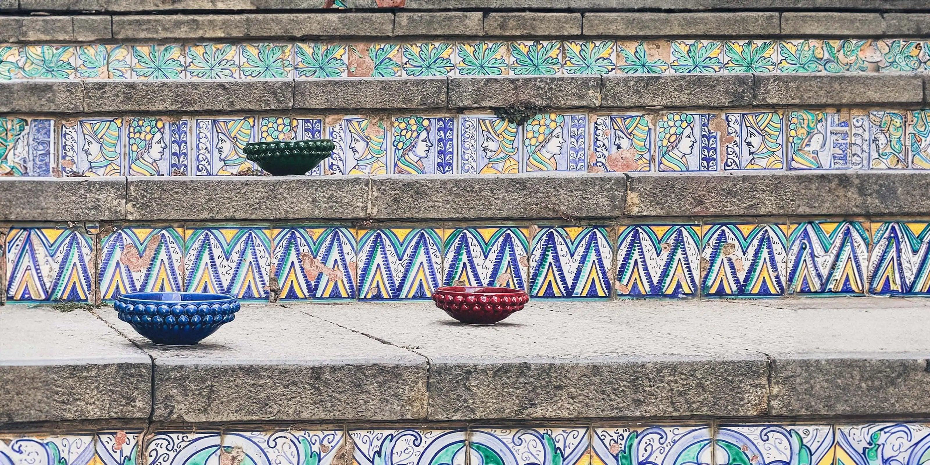 Ciotole a pigna in ceramica di Caltagirone fatte a mano su scala decorata con maioliche colorate.