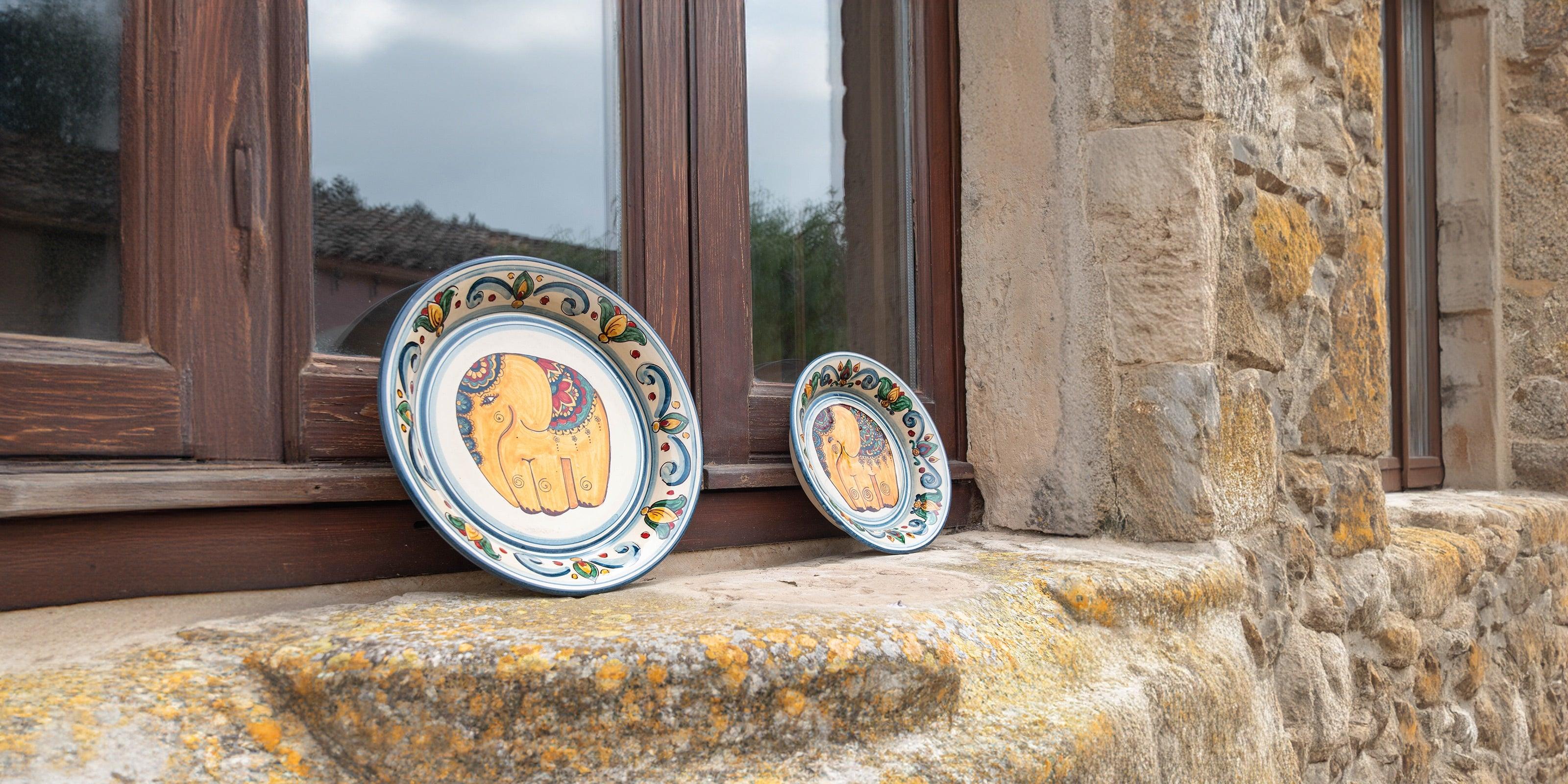 due piatti di ceramiche di Caltagirone fatti a mano con elefanti decorativi su davanzale in pietra rustica
