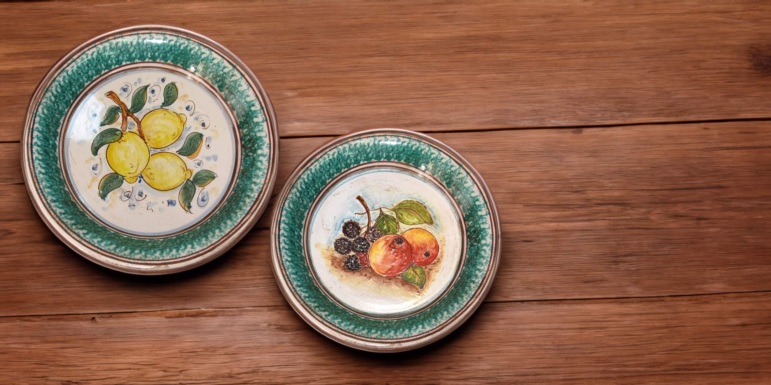 Due piatti in ceramica di Caltagirone fatti a mano con decorazioni di limoni e frutti su sfondo verde