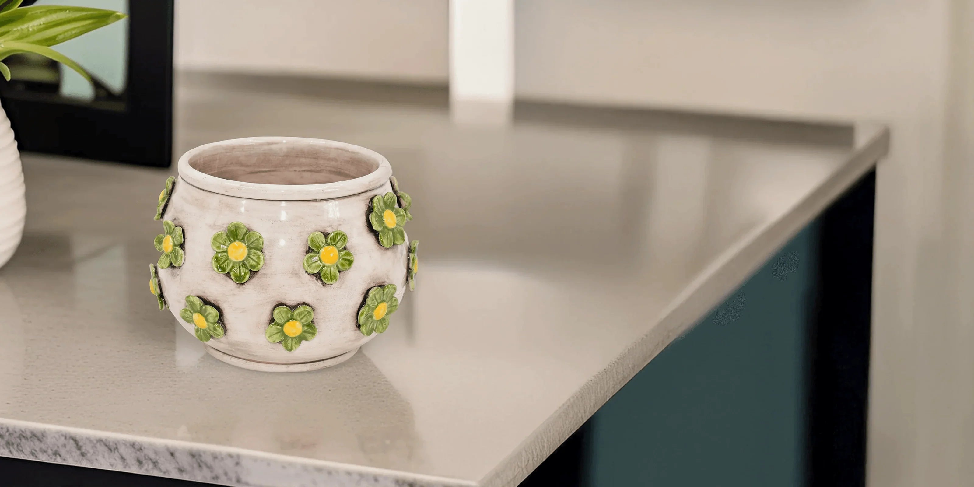 Vaso bianco con fiori verdi e gialli in ceramica di Caltagirone fatti a mano su piano cucina chiaro