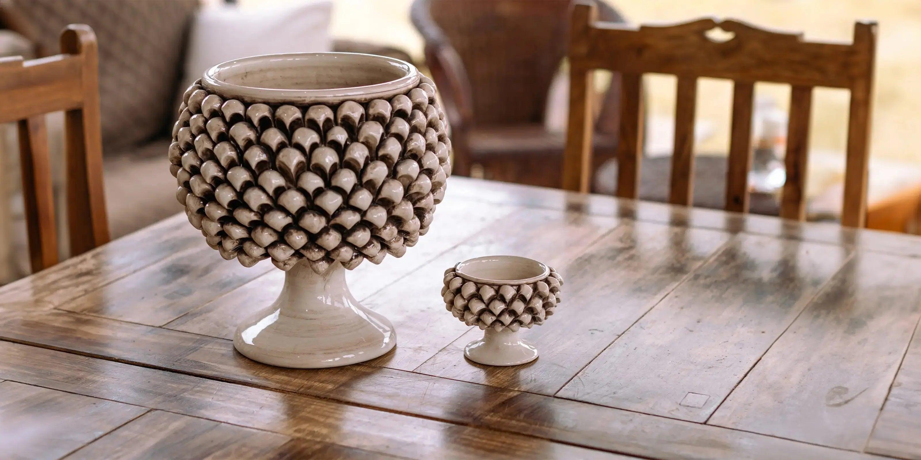 Ceramiche Caltagirone fatti a mano: due vasi decorativi bianchi con rilievi a conchiglia su tavolo di legno