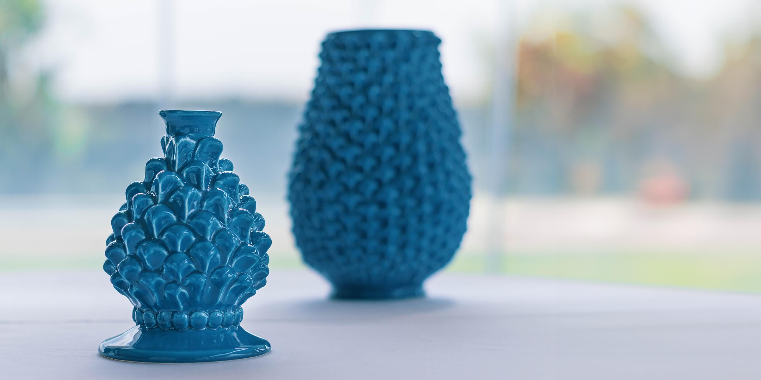 Portacandela a pigna e vaso blu in ceramiche Caltagirone fatti a mano su tavolo bianco