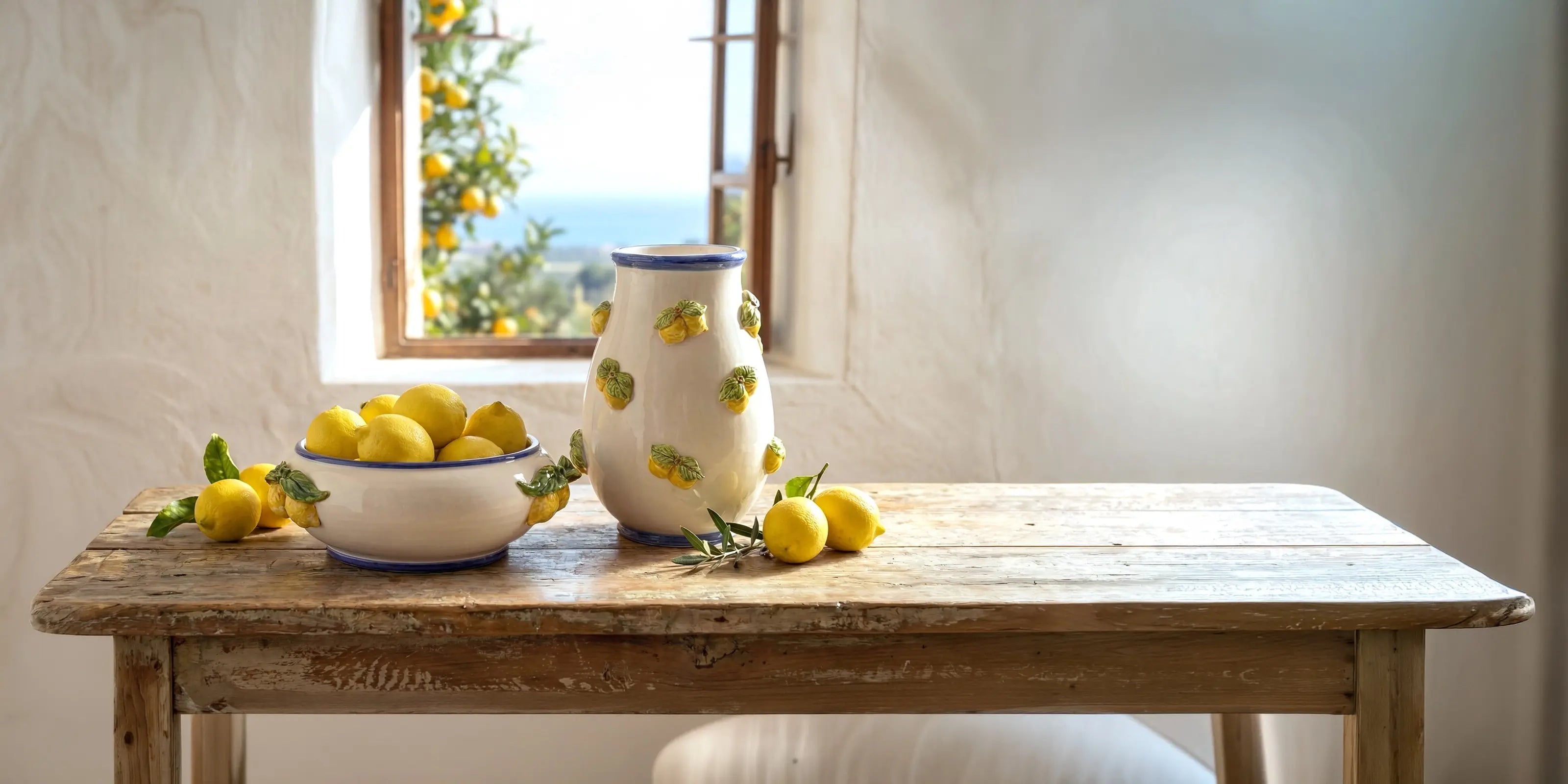 Ceramiche Caltagirone fatti a mano con decorazioni di limoni su tavolo di legno rustico davanti a finestra aperta con vista su limoni
