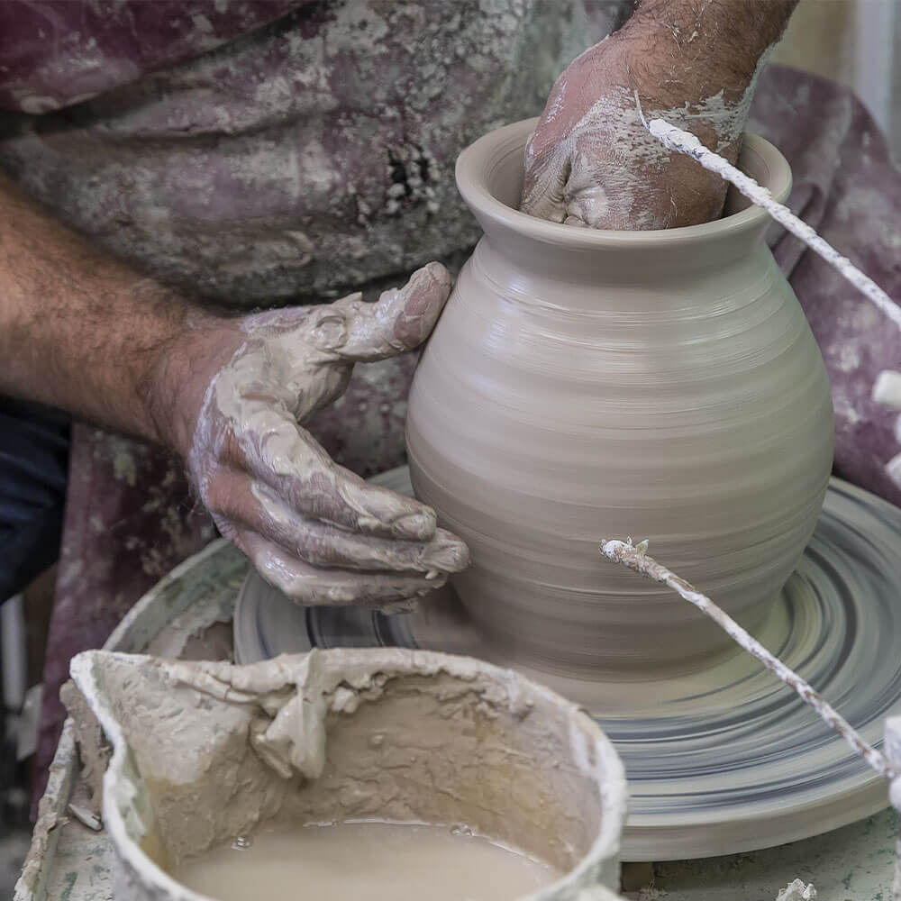 Le fasi di lavorazione delle Ceramiche di Caltagirone Sofia, delle mani modellano la creta su un torneo e diventerà un vaso