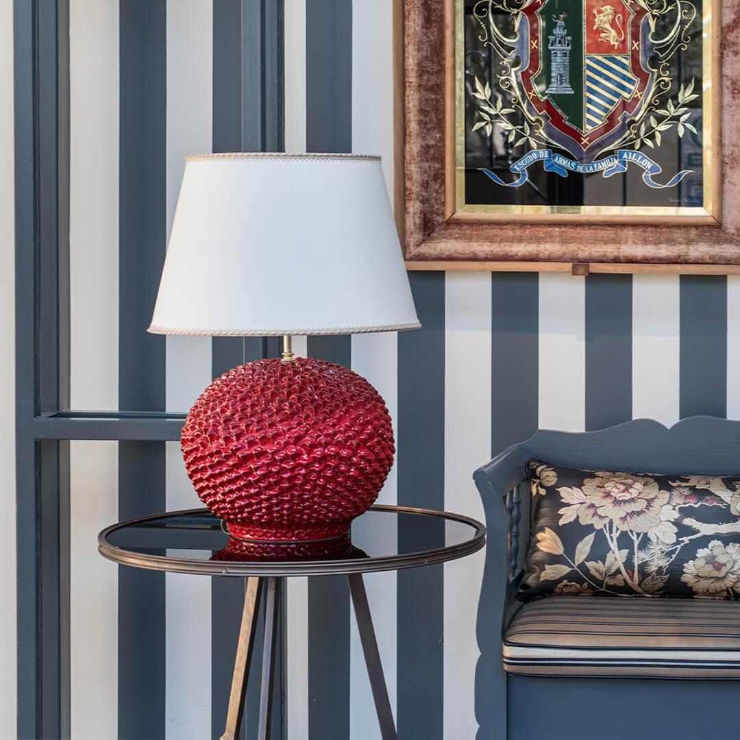 Lume palla a pigna rosso fuoco in ceramica di Caltagirone fatti a mano su tavolino elegante.