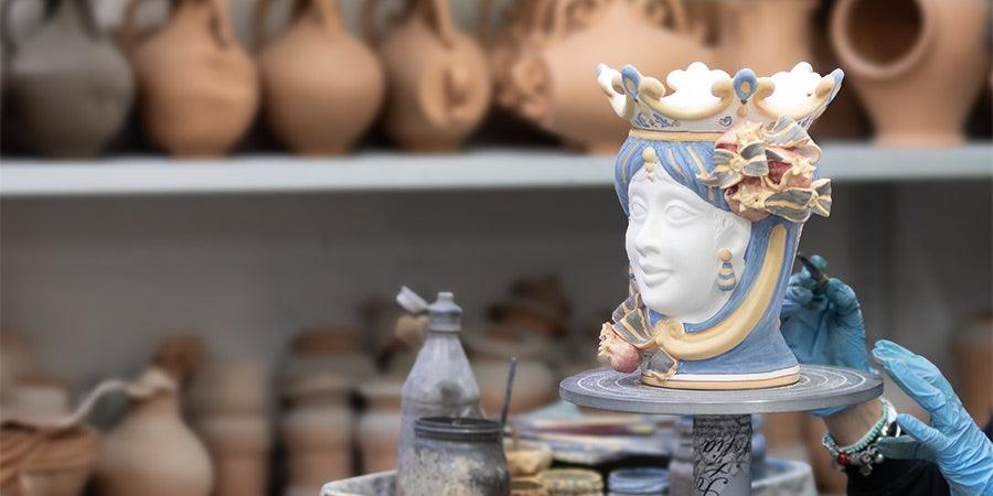 Decoratore al lavoro su testa di moro ceramiche Caltagirone fatti a mano, laboratorio artigianale.