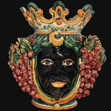 Ceramiche di Caltagirone fatti a mano con volto nero, corona e grappoli d'uva, arte tradizionale siciliana